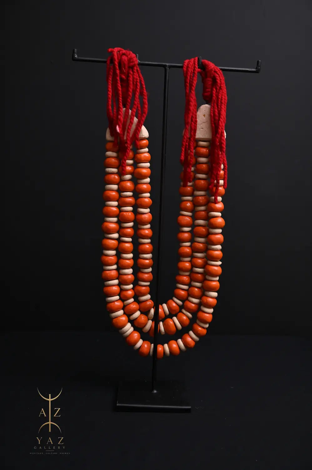 Sunset Ember Pendant Sculpture – Ivory & Orange Beads with Red Rope on Black Stand (62 x 34 cm)
