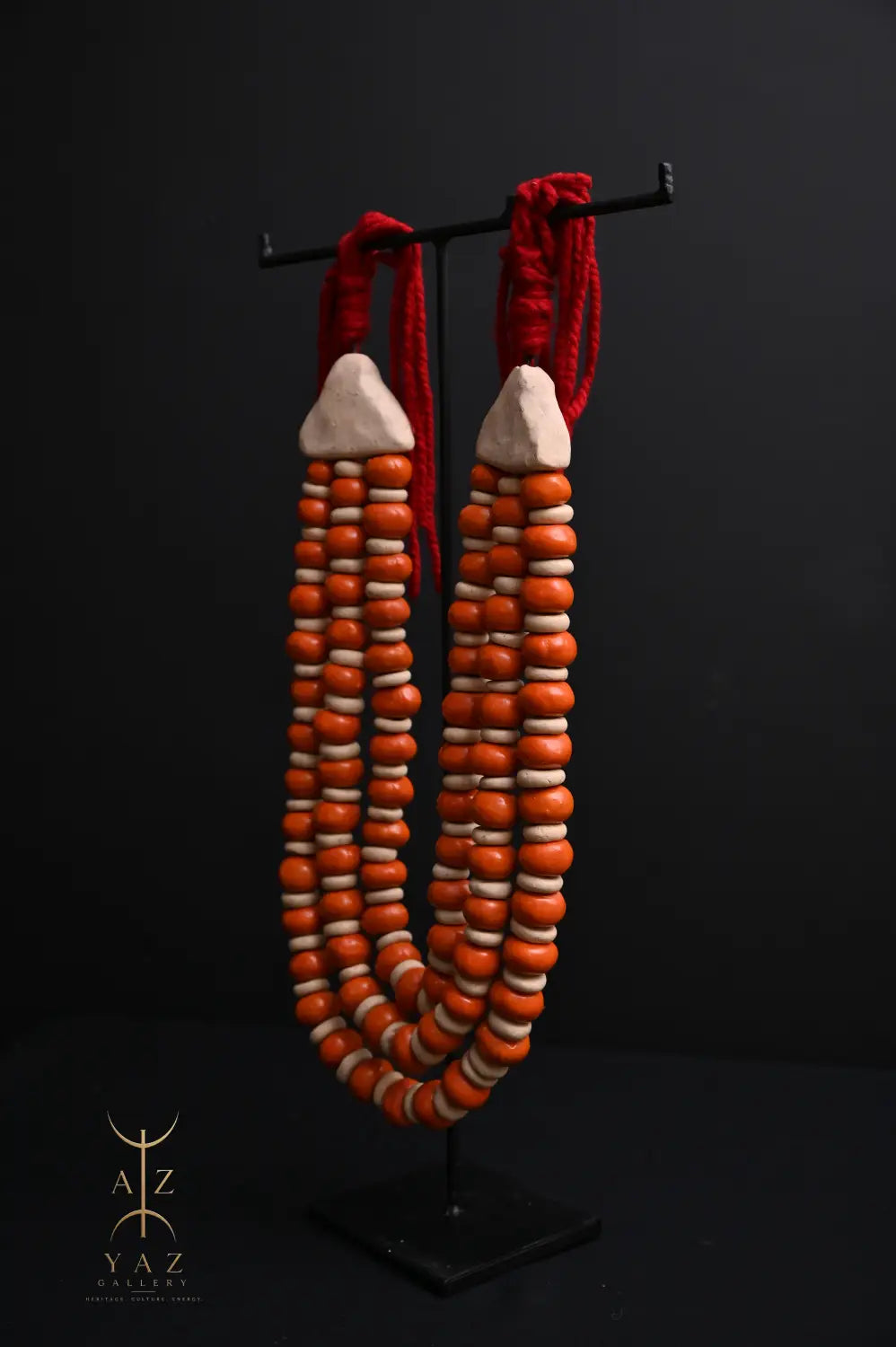 Sunset Ember Pendant Sculpture – Ivory & Orange Beads with Red Rope on Black Stand (62 x 34 cm)